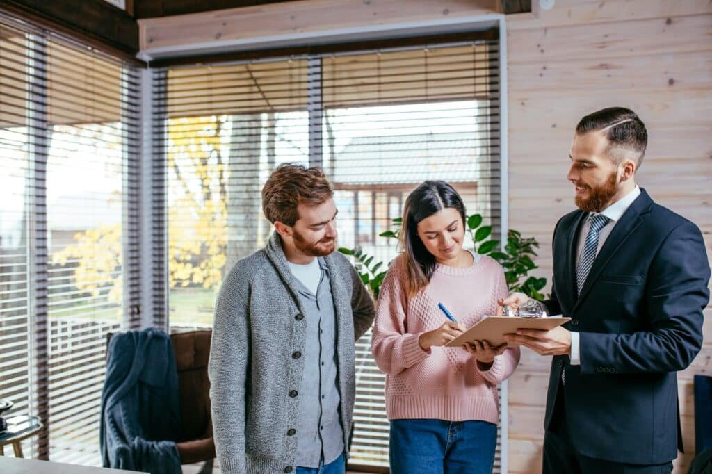 Couple customers signing papers with mortgage broker making purchase deal