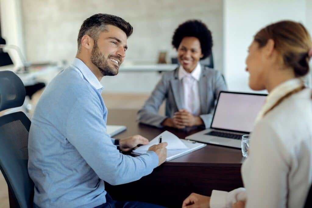 Happy couple signing mortgage agreement on a meeting with real estate agent.