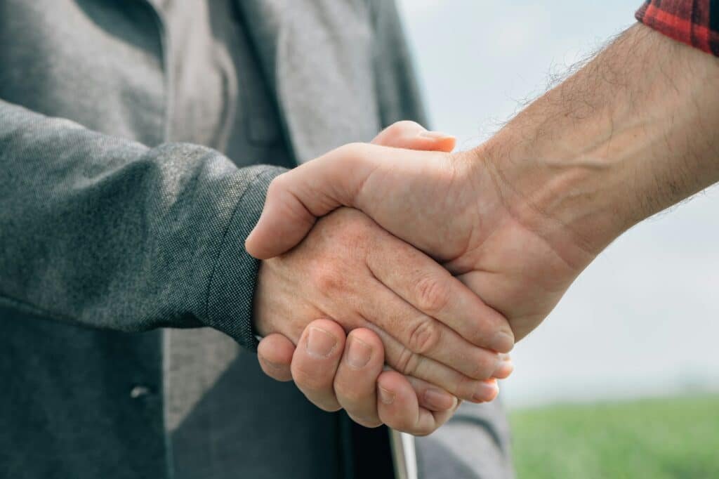 Mortgage loan officer and farmer shaking hands upon reaching an agreement