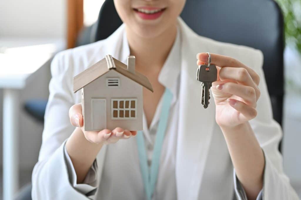 Real estate agent holding house model and keys. Mortgage and real estate investment concept.